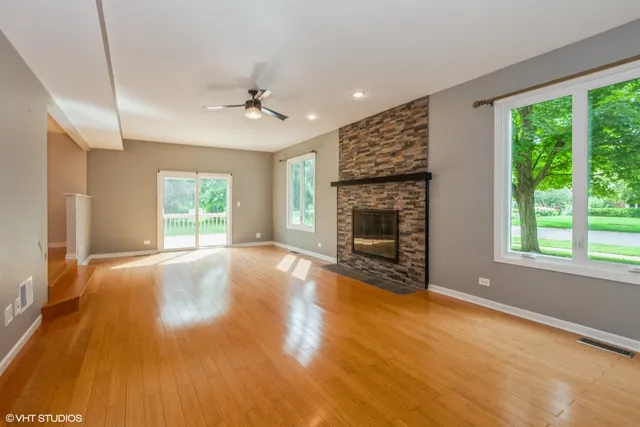 an empty room with windows fireplace and wooden floor