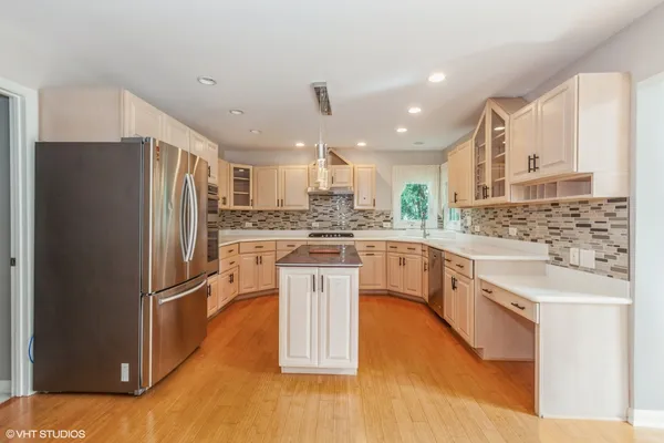 a kitchen with stainless steel appliances granite countertop a refrigerator a sink dishwasher a stove and white cabinets with wooden floor