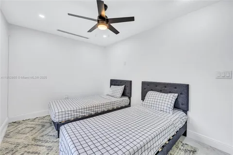 a bedroom with two beds and ceiling fan