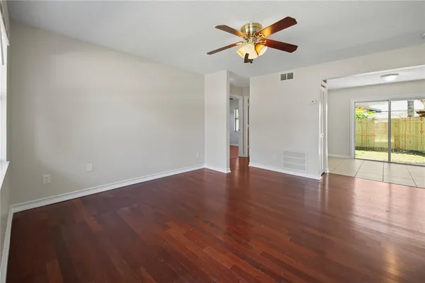 a view of an empty room with window and wooden floor