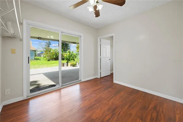 an empty room with wooden floor fan and windows