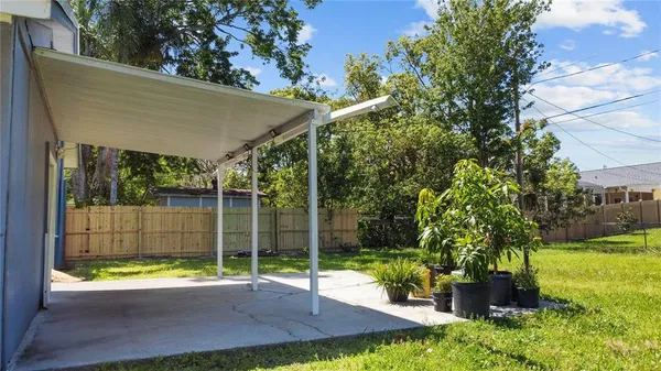 a view of a backyard with couches plants and large tree
