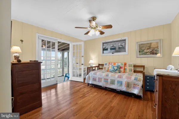 a view of a bedroom with wooden floor and a ceiling fan