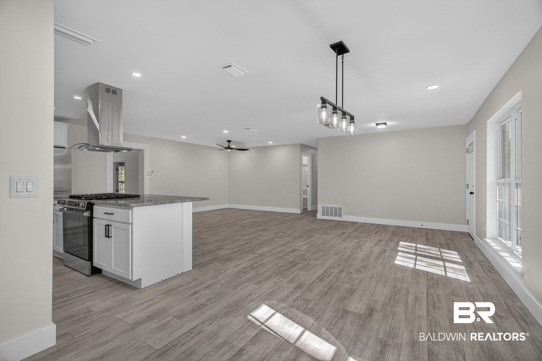 10650 Old Pascagoula Road Theodore, AL 36582 - Photo 33 of 77 Kitchen with dark stone counters, white cabinetry, stainless steel gas range, a ceiling fan, and island range hood