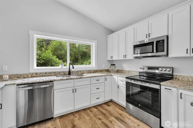 a kitchen with granite countertop stainless steel appliances white cabinets granite counter tops and a window