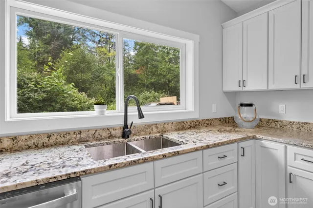 a kitchen with granite countertop white cabinets and a window