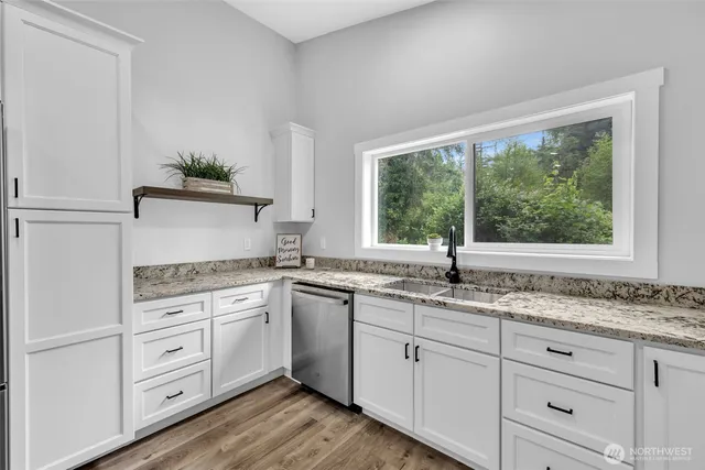 a kitchen with granite countertop white cabinets and a large window