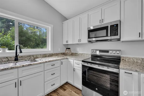a kitchen with stainless steel appliances granite countertop white cabinets and a stove top oven