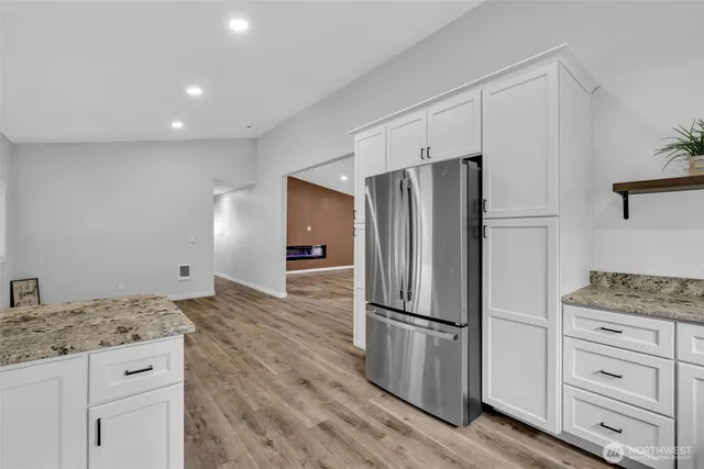a kitchen with granite countertop a refrigerator and a stove top oven