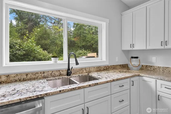 a kitchen with granite countertop white cabinets and a window