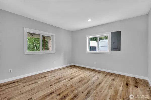 a view of an empty room with wooden floor and a window