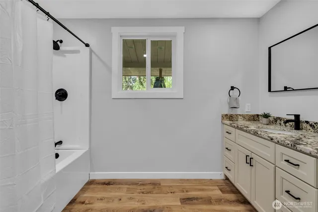 a bathroom with a granite countertop sink and a bathtub