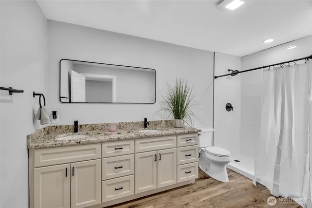a bathroom with a granite countertop sink toilet a large mirror and shower