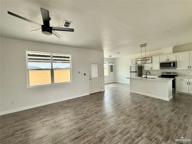 a kitchen with stainless steel appliances kitchen island a refrigerator sink and white cabinets