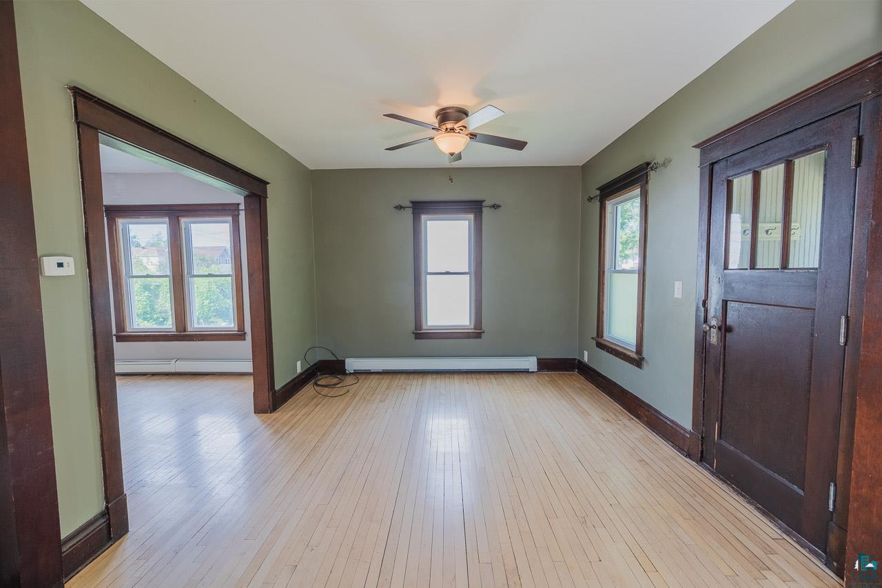 508 10th Street South Virginia, MN 55792 - Photo 5 of 43 Expansive room with light wood-finish flooring, dark wood trim, and a ceiling fan with integrated lighting