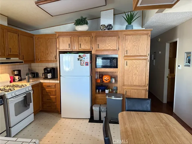 a kitchen with stainless steel appliances granite countertop a refrigerator a stove and a sink