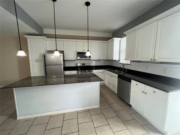 a kitchen with stainless steel appliances granite countertop a sink a stove and refrigerator