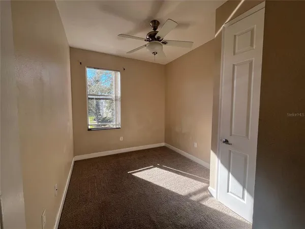 an empty room with a window and a ceiling fan