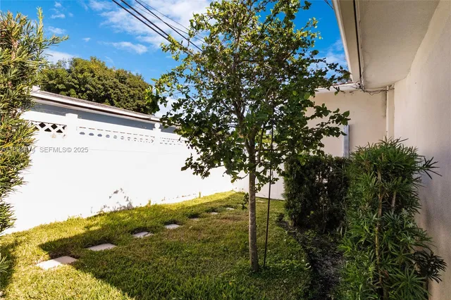 a view of a big yard with plants and large tree