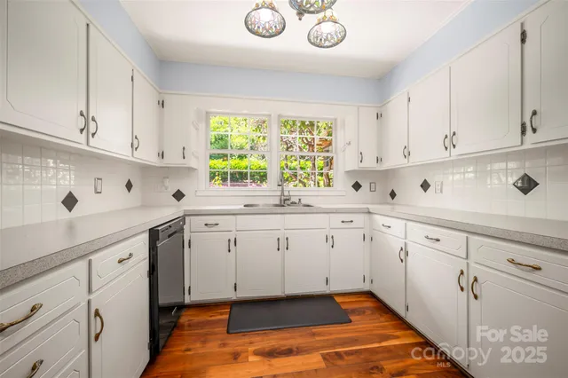 a kitchen with white cabinets and window