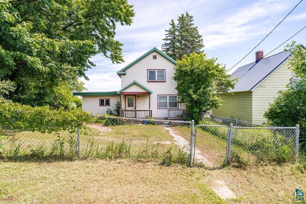 View of back of home with a fenced front yard and a gate