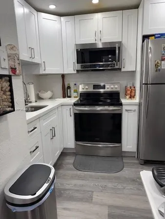 a kitchen with granite countertop a stove a microwave a sink a refrigerator and cabinets
