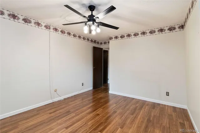 a view of a room with wooden floor and ceiling fan