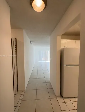 a view of a refrigerator in kitchen and an empty room