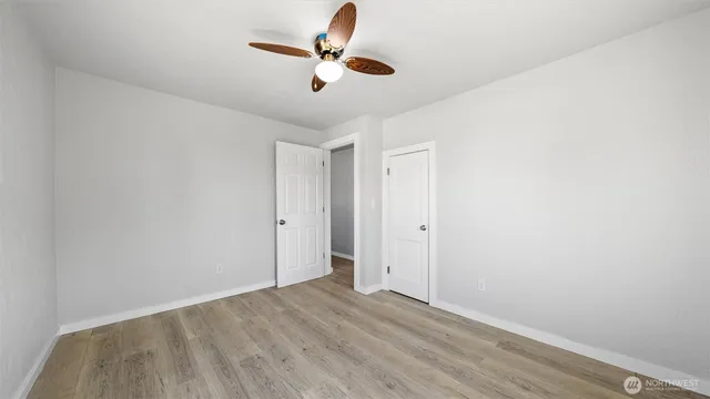 an empty room with wooden floor and ceiling fan