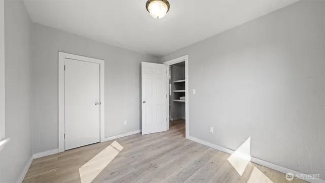 a view of an empty room with closet and a window