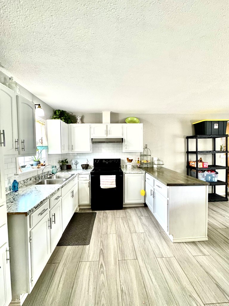 212 Way Drive Ingram, TX 78025 - Photo 6 of 22 a large kitchen with kitchen island a stove a sink dishwasher and white cabinets with wooden floor