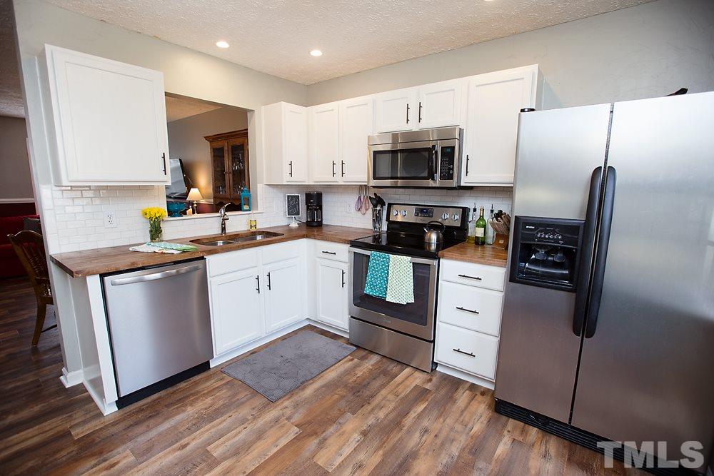 2225 Springhill Avenue Raleigh, NC 27603 - Photo 4 of 18 a kitchen with stainless steel appliances white cabinets a sink a stove a refrigerator and a microwave