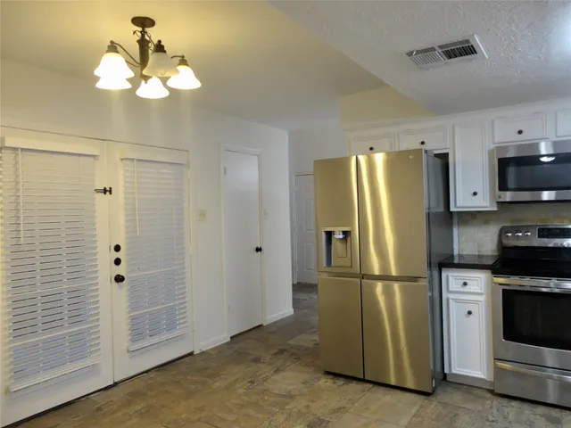 a kitchen with stainless steel appliances granite countertop a refrigerator a stove and a sink
