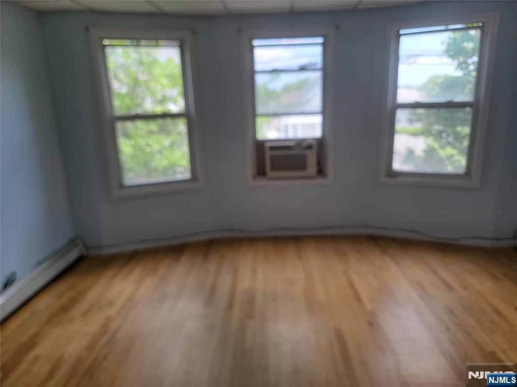165 Corabelle Avenue, Unit 2 Lodi, NJ 07644 - Photo 4 of 7 an empty room with wooden floor and windows