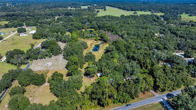 an aerial view of residential house with outdoor space and trees all around