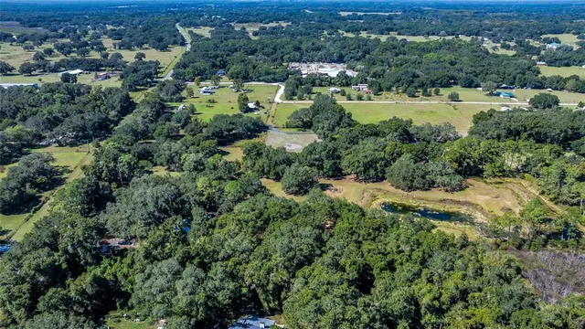 an aerial view of residential house with outdoor space and trees all around