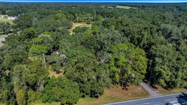 an aerial view of residential house with outdoor space and trees all around