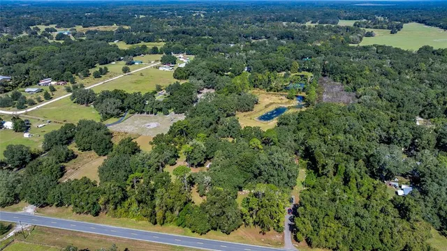 an aerial view of residential house with outdoor space and trees all around