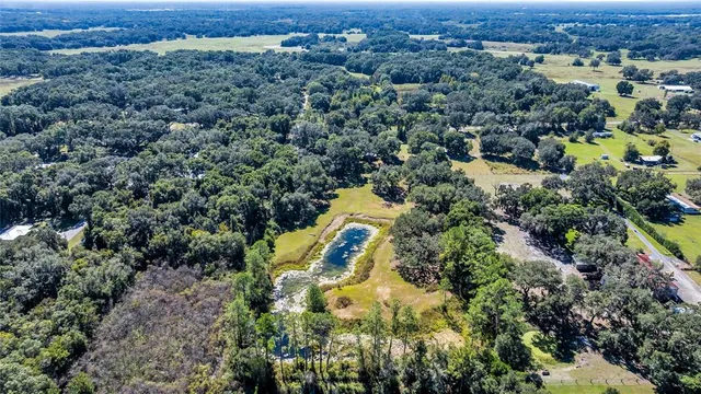an aerial view of residential house with outdoor space and trees all around
