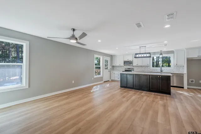 a large kitchen with stainless steel appliances granite countertop a sink cabinets and wooden floor