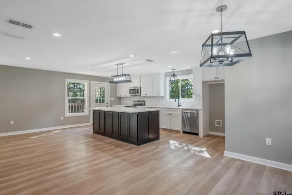 a kitchen with stainless steel appliances granite countertop a sink cabinets and wooden floor