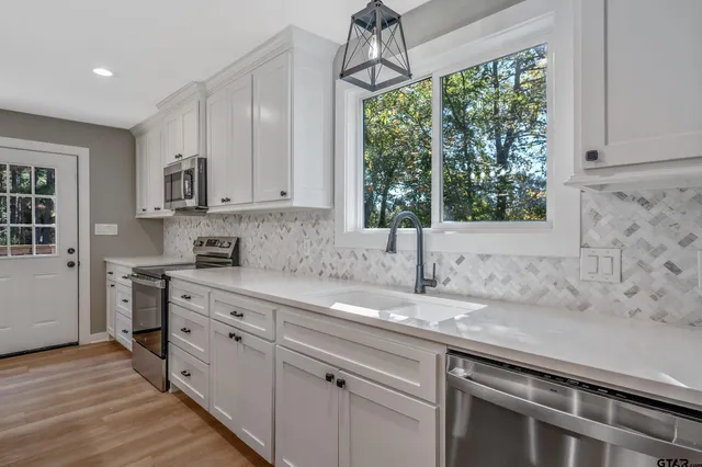 a kitchen with stainless steel appliances granite countertop a sink a stove and a wooden floors