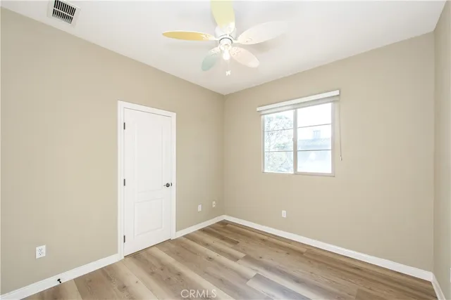 an empty room with windows and ceiling fan