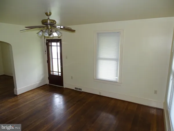 an empty room with wooden floor fan and windows