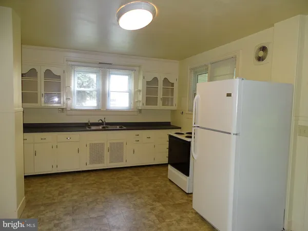 a kitchen with a refrigerator a stove top oven and cabinets