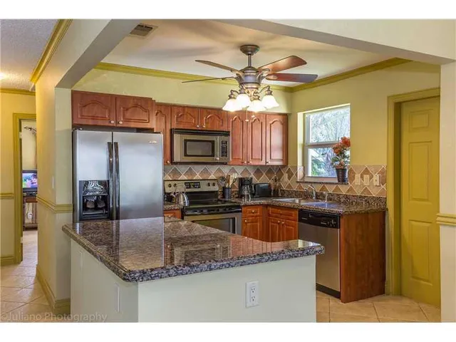 a kitchen with kitchen island granite countertop a sink cabinets and stainless steel appliances