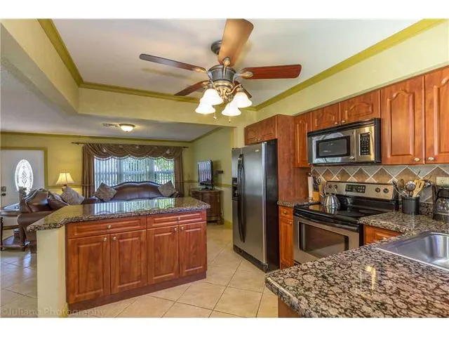 a kitchen with stainless steel appliances kitchen island granite countertop a stove refrigerator and microwave