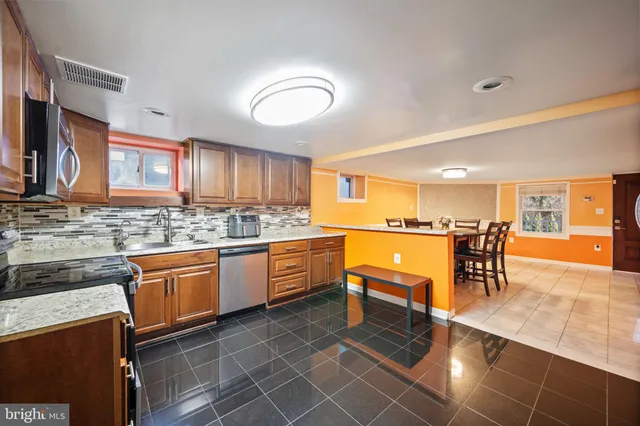 a kitchen with stainless steel appliances granite countertop table chairs sink and cabinets