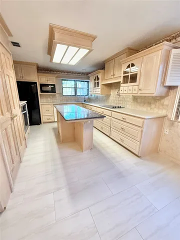 a large white kitchen with stainless steel appliances granite countertop a stove and a sink