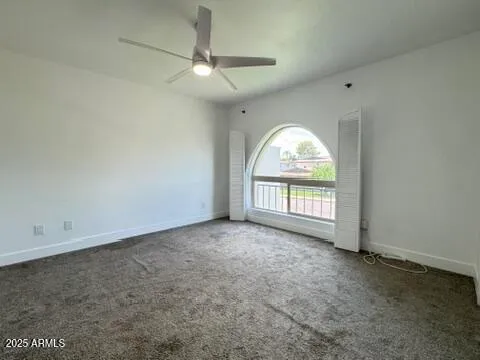 an empty room with a chandelier fan and windows